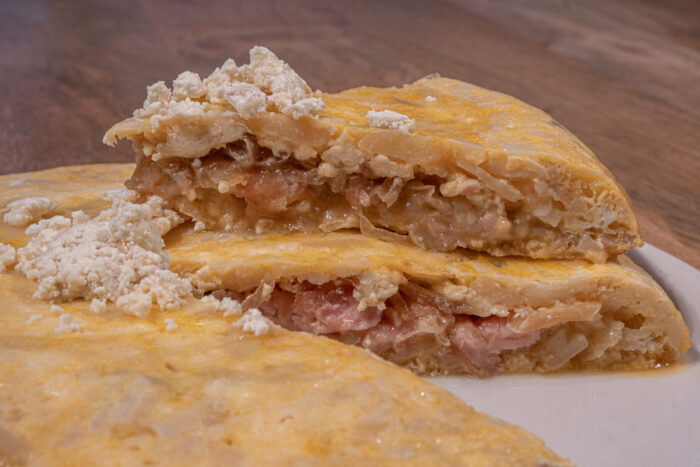 Tortilla de patatas rellena de queso de cabra sobre plato blanco