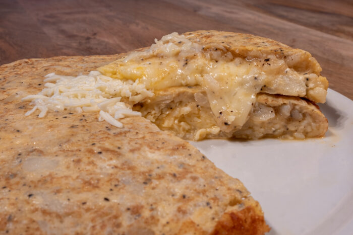 Tortilla de patatas rellena de queso y trufa sobre plato blanco