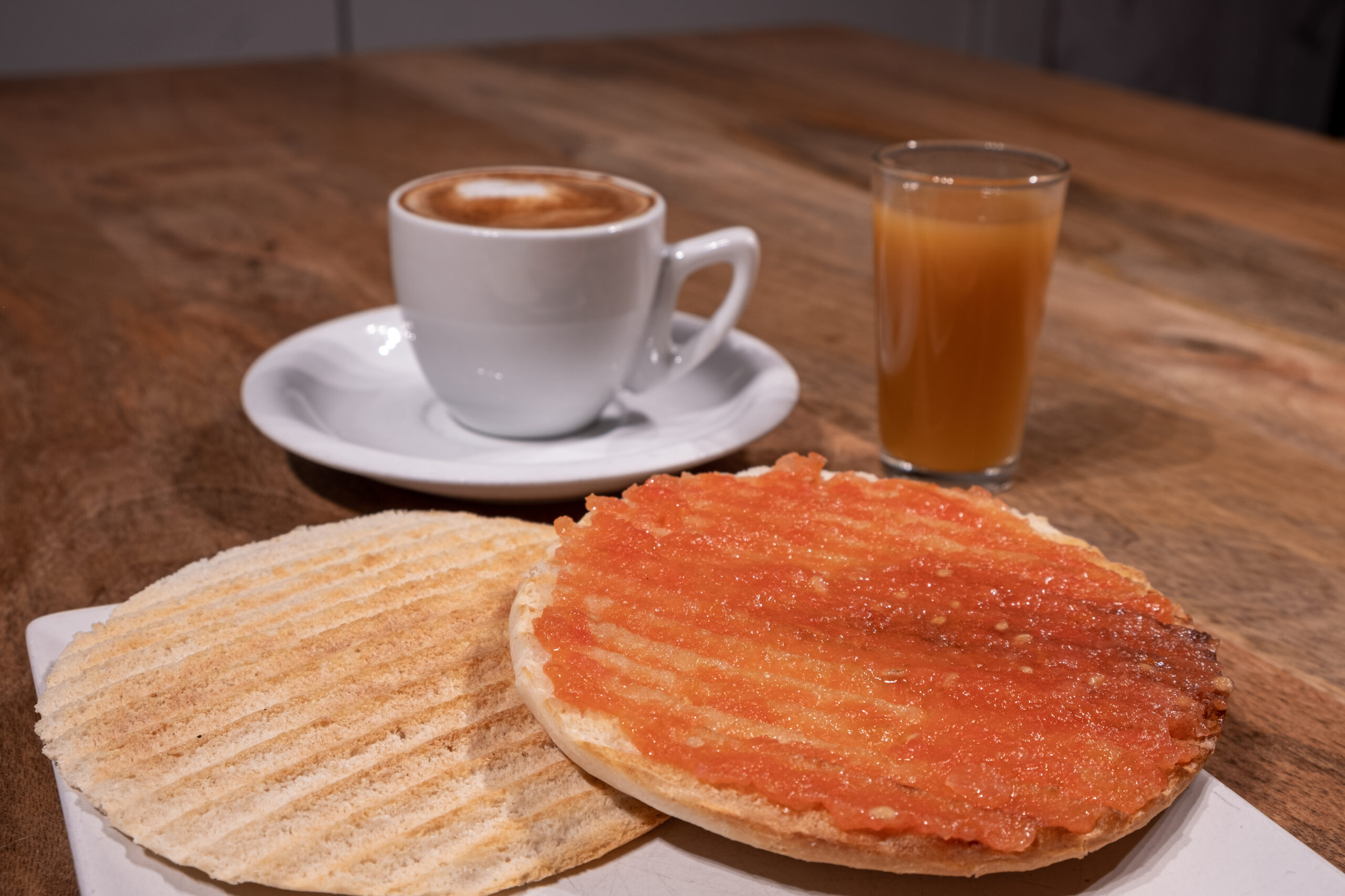 Desayuno Piraña con tomate natural untado sobre un mollete, zumo y café
