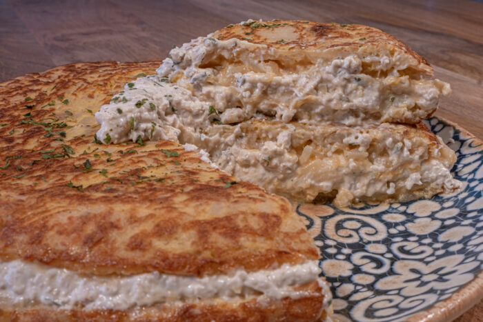 Tortilla de patatas rellena de pollo alioli sobre plato de colores